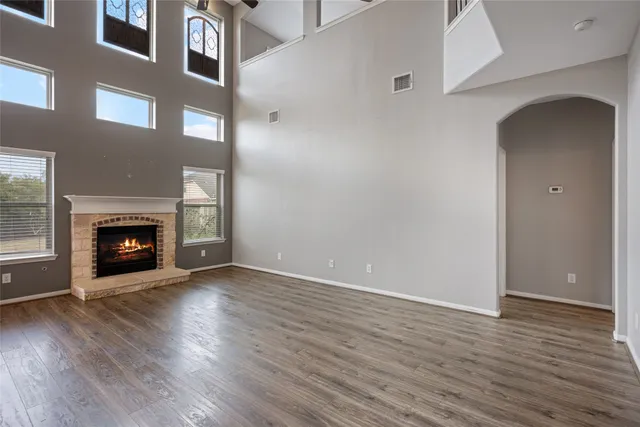 an empty room with wooden floor fireplace and windows