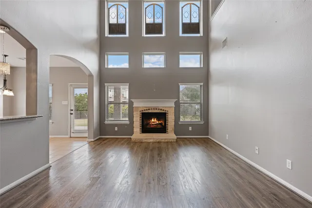 a view of an empty room with wooden floor fireplace and a window