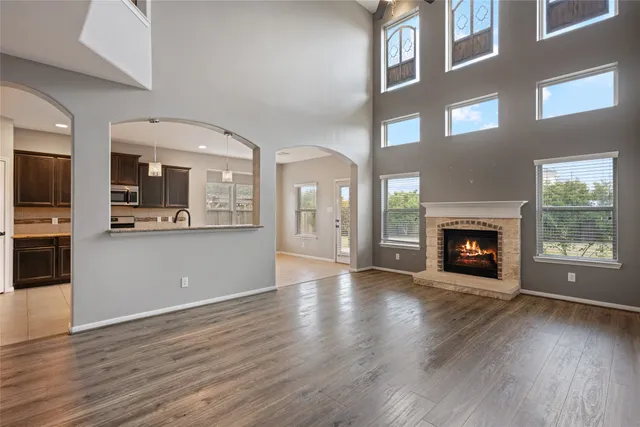 a view of a living room with stainless steel appliances wooden floor and a kitchen