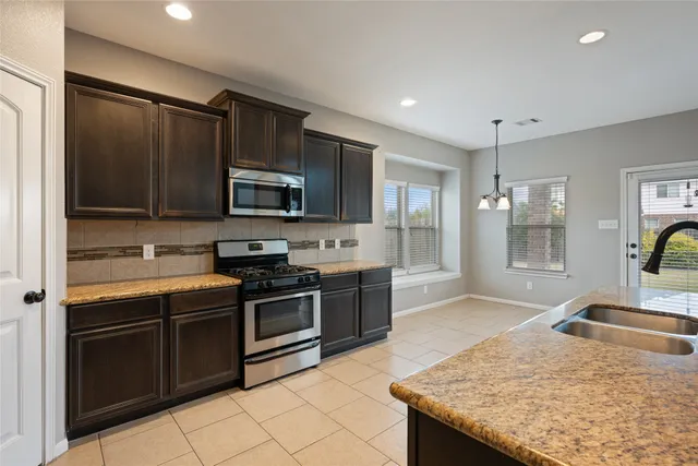 a kitchen with stainless steel appliances granite countertop a stove microwave and sink