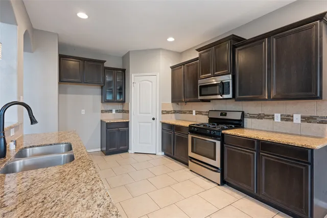 a kitchen with stainless steel appliances granite countertop a stove top oven a sink dishwasher a refrigerator and a microwave