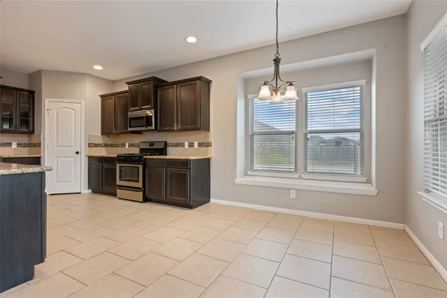 a kitchen with stainless steel appliances granite countertop a stove top oven a sink and a refrigerator