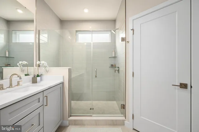 a bathroom with a shower sink vanity and mirror