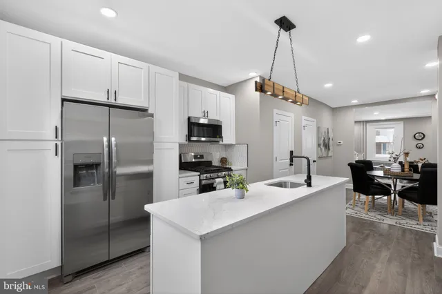 a kitchen with kitchen island a counter top space a sink stainless steel appliances and cabinets