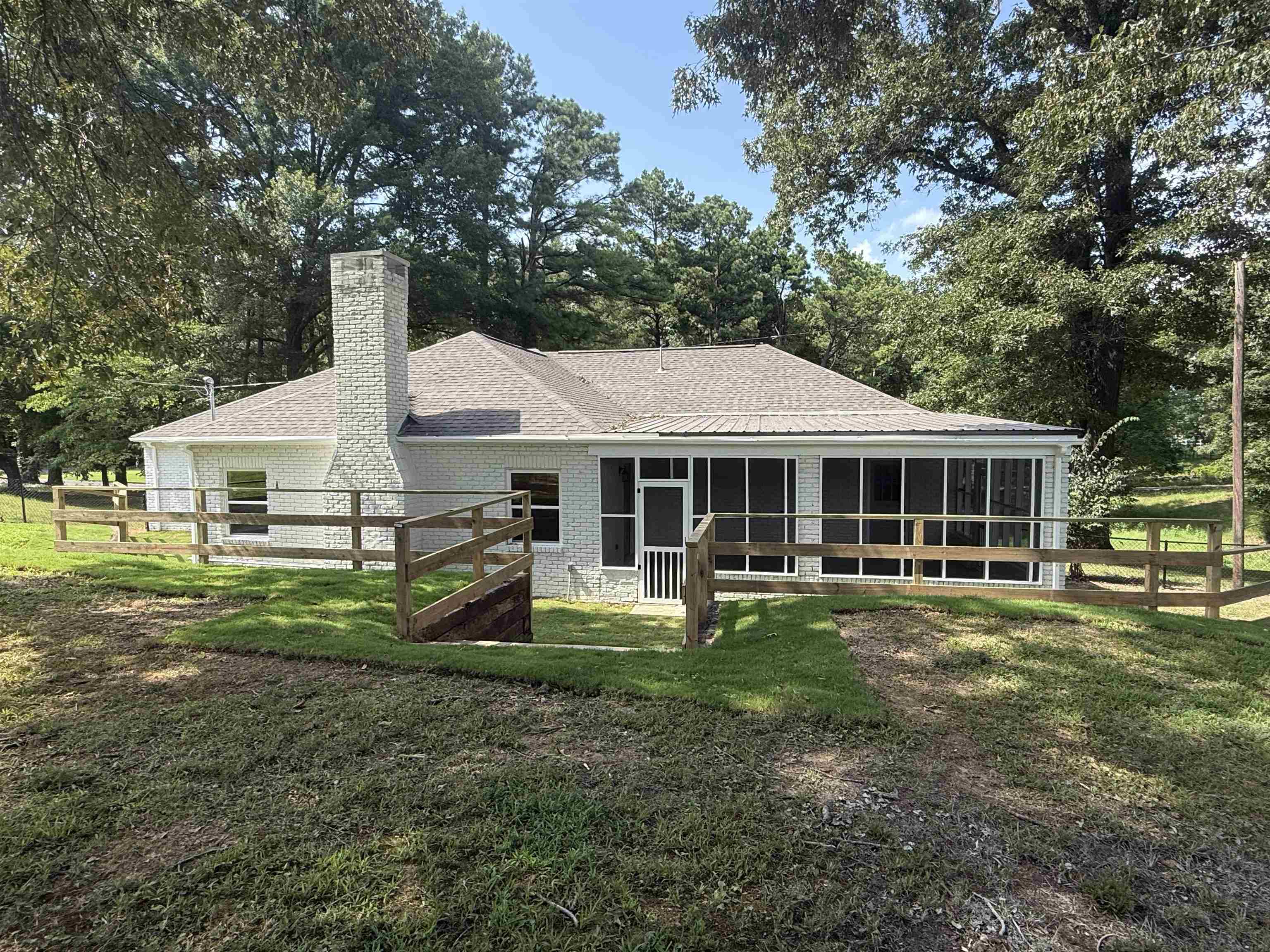 1835 Pleasant Grove Road Moscow, TN 38057 - Photo 28 of 34 White brick exterior featuring a screened-in porch with a gabled roof, a large brick chimney, and a surrounding wooden fence