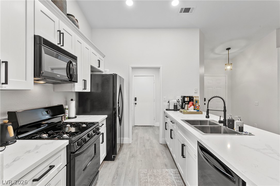 101 Beaver Ridge Avenue North Las Vegas, NV 89031 - Photo 9 of 42 White cabinetry, sleek appliances, and light flooring create a contemporary kitchen setting.