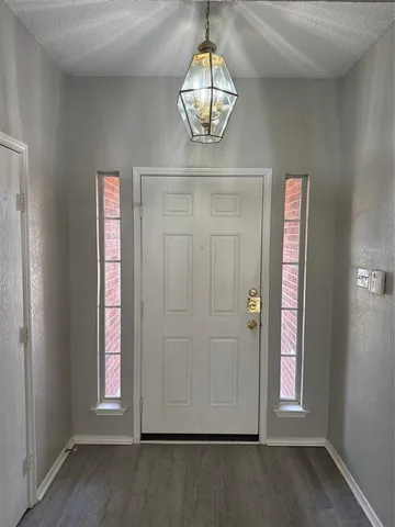 an empty room with wooden floor cabinet and windows