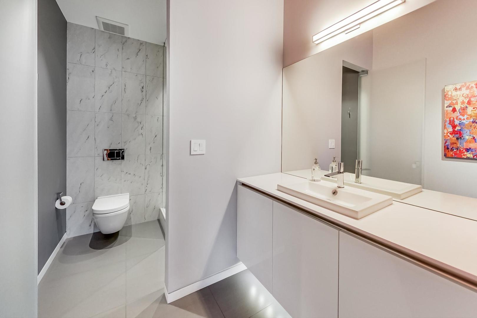 1327 West Washington Boulevard, Unit 2H Chicago, IL 60607 - Photo 15 of 31 a bathroom with a granite countertop sink a toilet and a large mirror