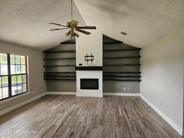 a view of a room with wooden floor staircase and a kitchen space