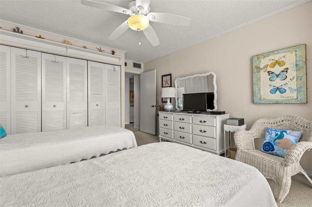 1 Key Capri, Unit 104E Treasure Island, FL 33706 - Photo 24 of 45 a bedroom with a bed a dresser and a flat screen tv