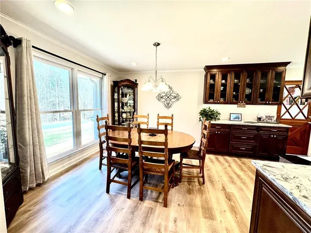 a living room with stainless steel appliances kitchen island granite countertop a table chairs and wooden floor