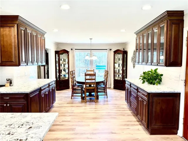 a kitchen with stainless steel appliances kitchen island granite countertop a refrigerator stove top oven dining table and chairs