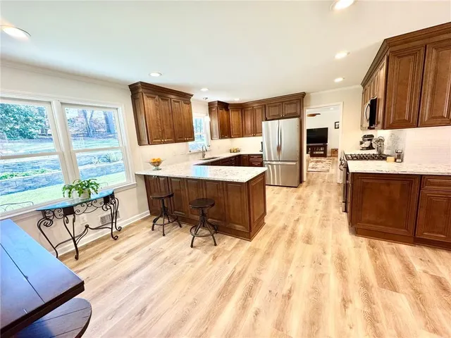 a living room with stainless steel appliances kitchen island granite countertop a sink and cabinets