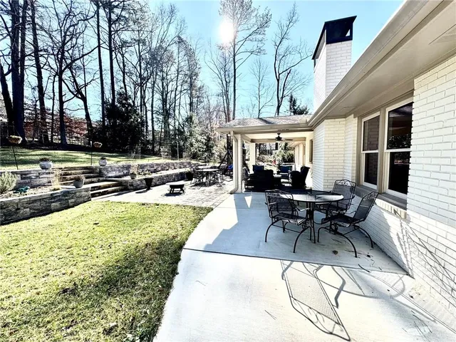 a view of a white house with a large pool and lawn chairs under an umbrella