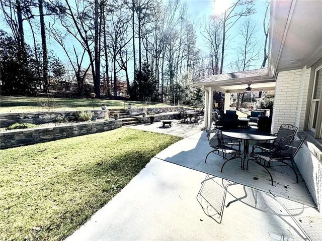 a view of a white house next to a road with big trees