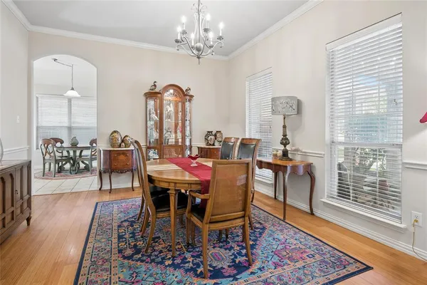 a dining room with chandelier and wooden floor