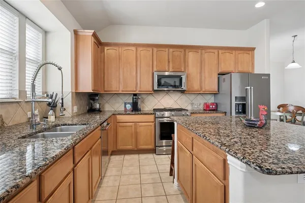 a kitchen with stainless steel appliances granite countertop a sink dishwasher stove refrigerator and cabinets