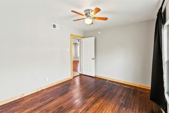 an empty room with wooden floor and ceiling fan
