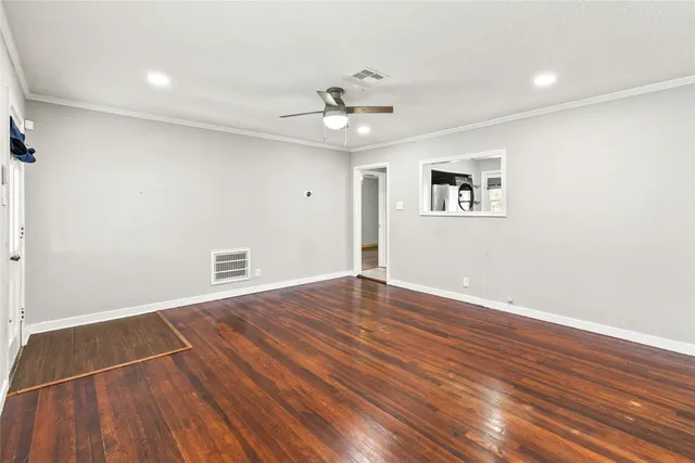 a view of an empty room with wooden floor and a ceiling fan