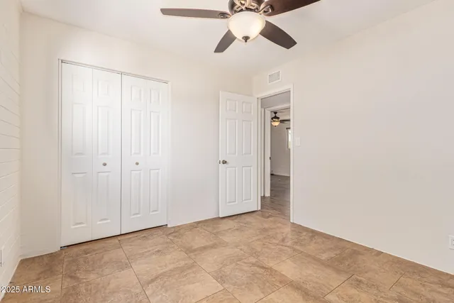 a view of an empty room and chandelier fan