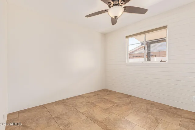an empty room with a window and a fan