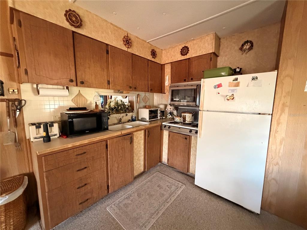 56340 Acorn Road Astor, FL 32102 - Photo 8 of 21 a kitchen with refrigerator a stove a sink and cabinets
