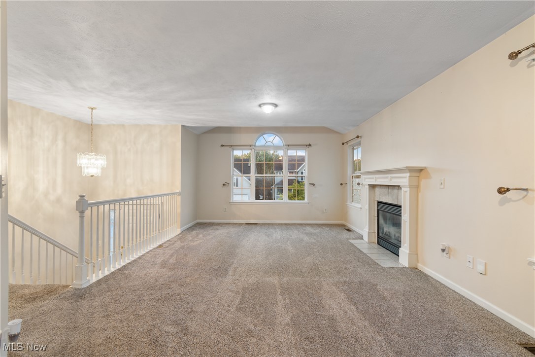 1333 Derbydale Road Akron, OH 44306 - Photo 5 of 29 Unfurnished living room featuring a tile fireplace, carpet flooring, and a chandelier