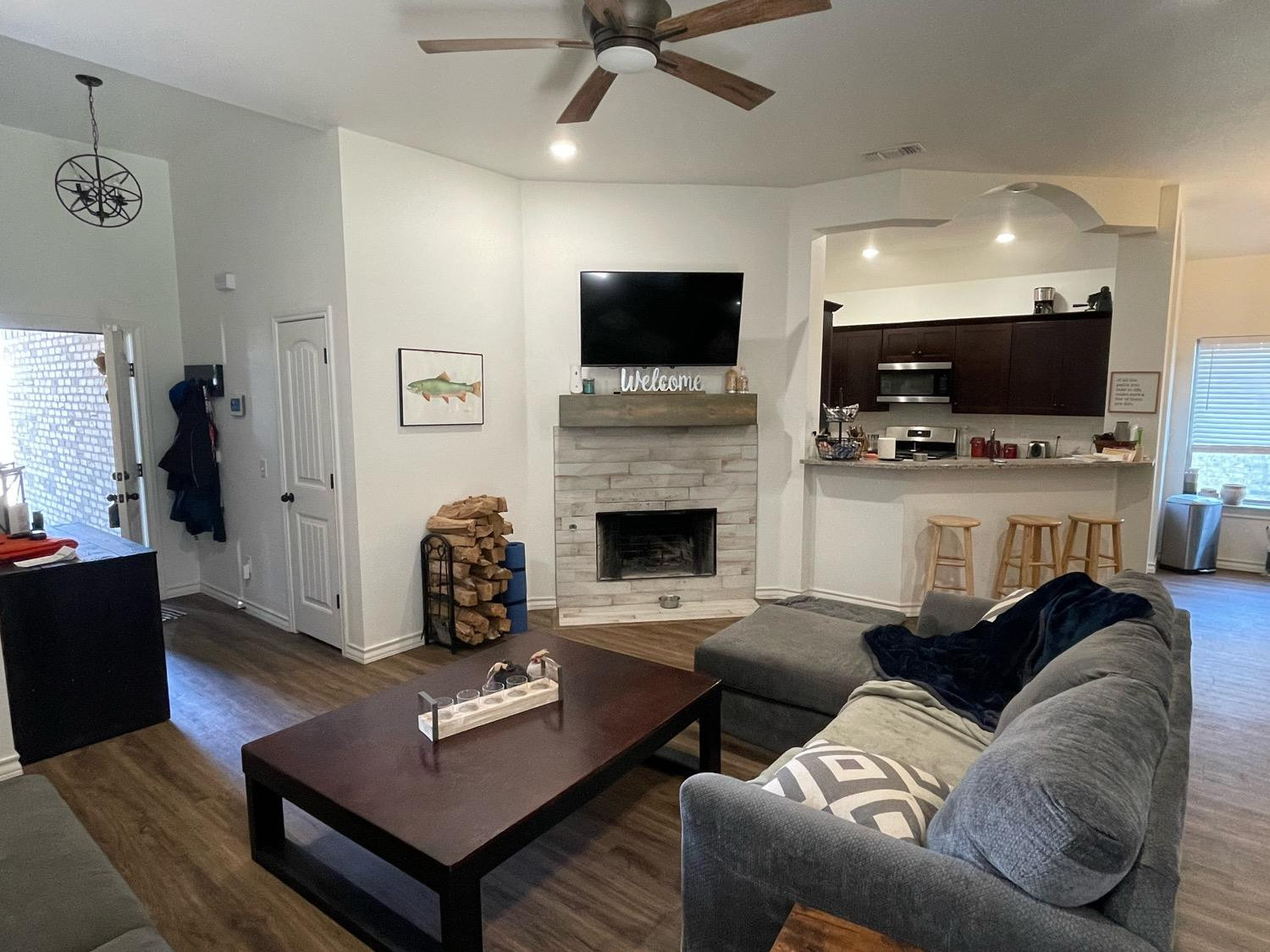 1707 100th Street Lubbock, TX 79423 - Photo 2 of 12 a living room with furniture a flat screen tv and a fireplace