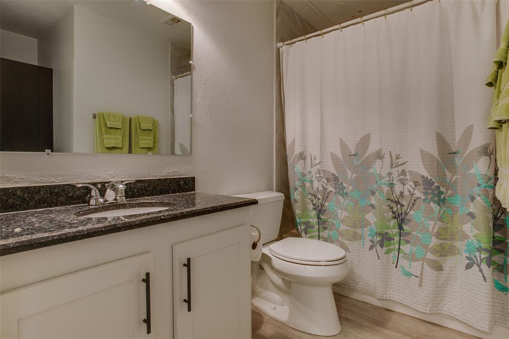 3105 San Jacinto Street, Unit 104 Dallas, TX 75204 - Photo 30 of 36 a bathroom with a granite countertop sink a toilet and a mirror