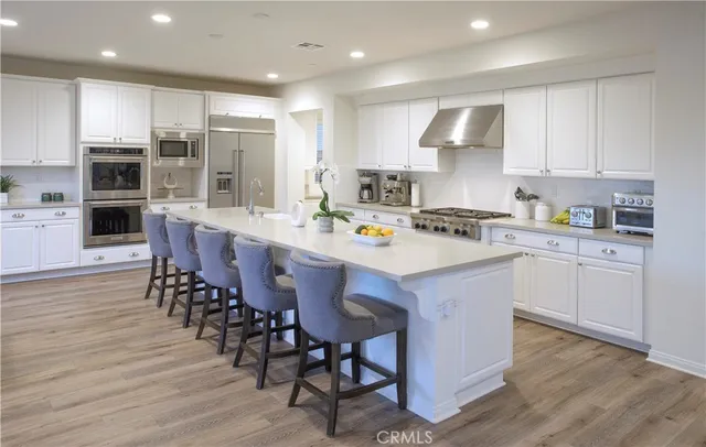a kitchen with a sink a center island stainless steel appliances and cabinets