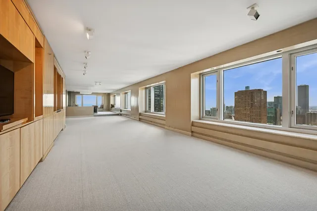 a bedroom with a large bed a flat screen tv and windows