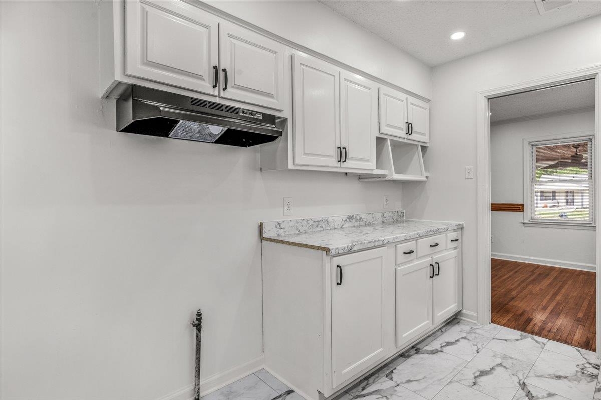 1244 Wells Station Road Memphis, TN 38122 - Photo 16 of 36 Kitchen with white cabinets, light countertops, light marble finish floors, recessed lighting, and a textured ceiling