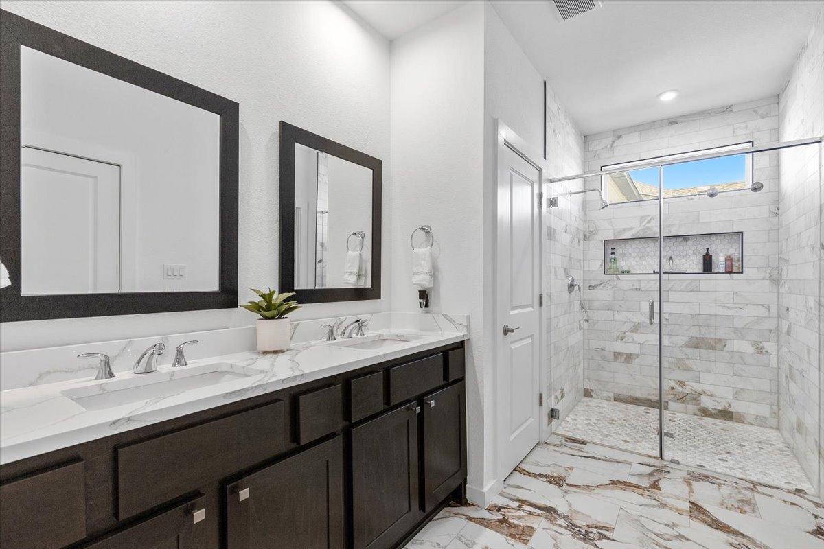 1904 Varese Path Leander, TX 78641 - Photo 9 of 37 Dual vanities and a spacious walk-in shower elevate this contemporary primary bathroom.