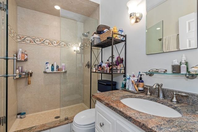 a bathroom with a granite countertop sink a toilet and shower