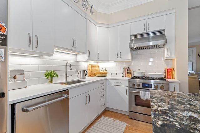 a kitchen with a sink cabinets stainless steel appliances and a window