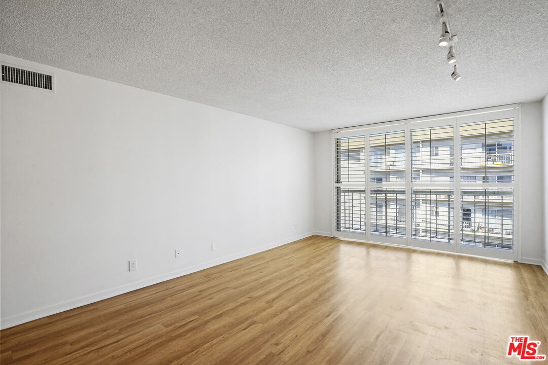 10751 Wilshire Boulevard, Unit PH 6 Los Angeles, CA 90024 - Photo 13 of 41 a view of an empty room with wooden floor and a window