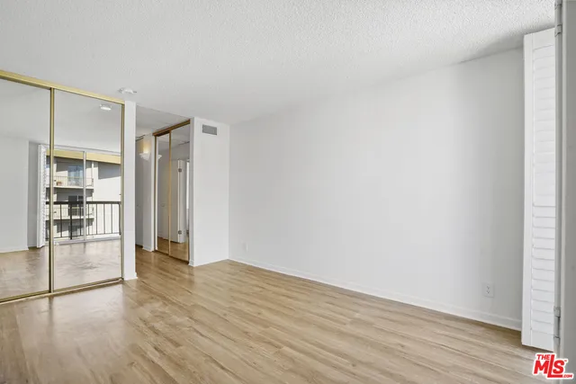 a view of an empty room with wooden floor and closet