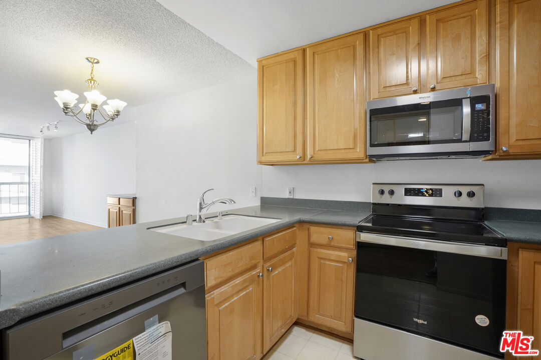 10751 Wilshire Boulevard, Unit PH 6 Los Angeles, CA 90024 - Photo 6 of 41 a kitchen with stainless steel appliances granite countertop a sink dishwasher a stove microwave and oven with wooden floor