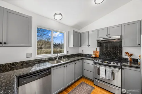 a kitchen with stainless steel appliances granite countertop a sink stove cabinets and a counter space
