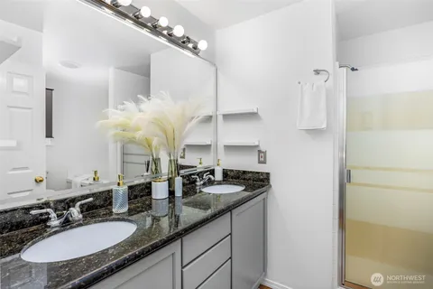 a bathroom with a granite countertop sink a mirror and a shower