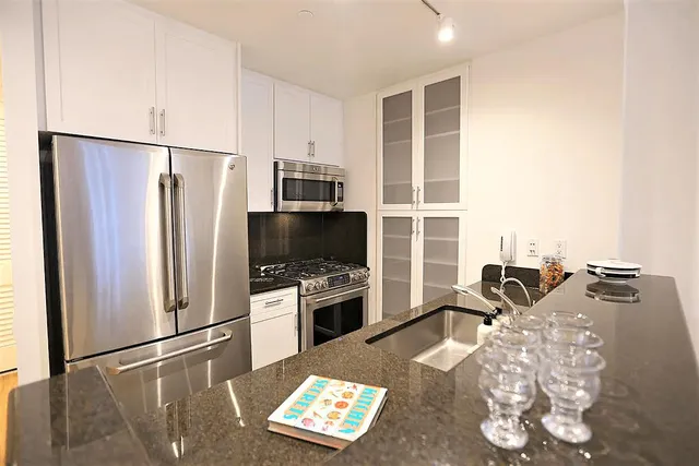 a living room with furniture a flat screen tv and a refrigerator