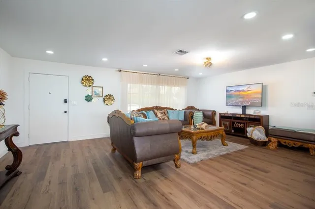 a living room with furniture a flat screen tv and kitchen view