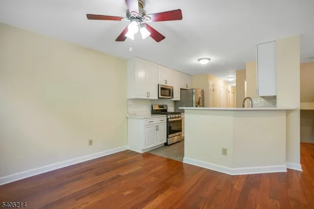 a kitchen with a refrigerator a stove cabinets and wooden floor