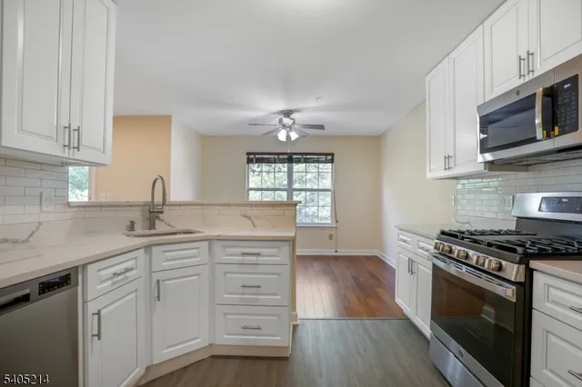 a kitchen with granite countertop a sink cabinets stainless steel appliances and a window