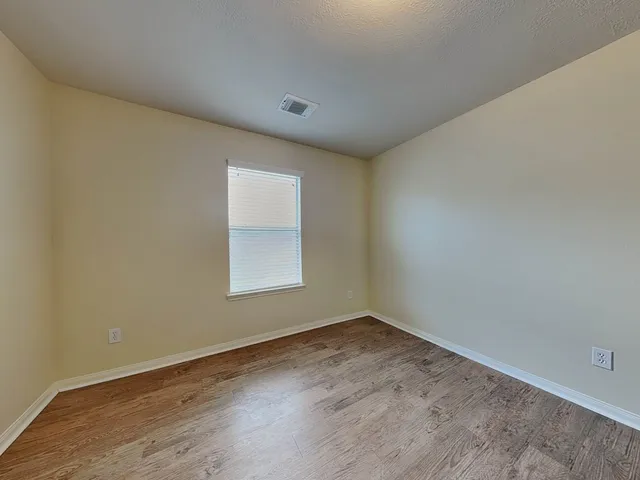 a view of an empty room and wooden floor & window