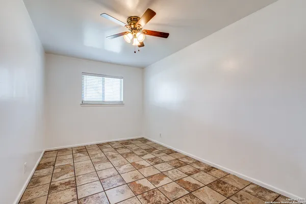 an empty room with a chandelier fan and windows