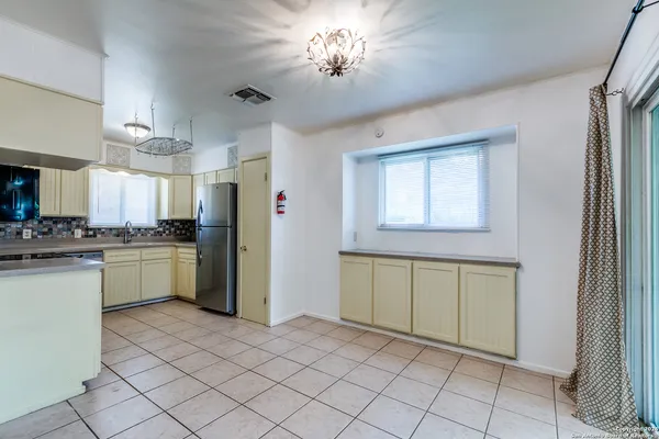 a view of a kitchen with a sink and dishwasher a refrigerator with white cabinets