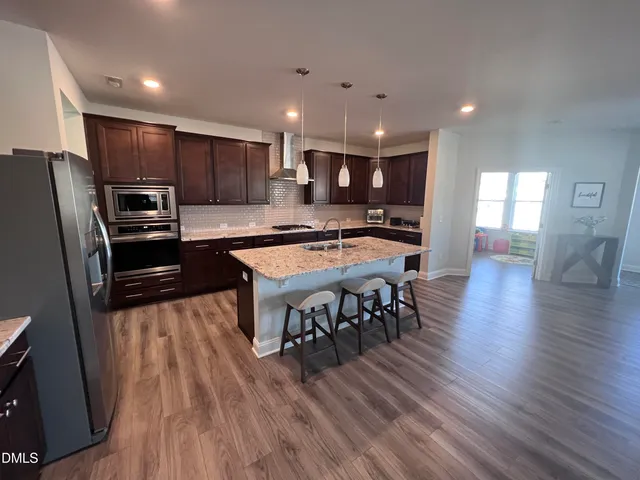 an open kitchen with kitchen island wooden floor center island and stainless steel appliances