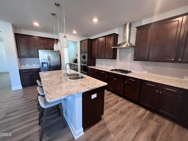 a kitchen with stainless steel appliances kitchen island granite countertop a sink a stove counter space and wooden floor