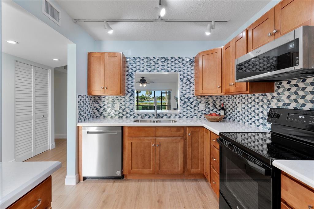 2900 Southwest 22nd Circle, Unit 221E Delray Beach, FL 33445 - Photo 11 of 43 a kitchen with stainless steel appliances a sink stove and cabinets